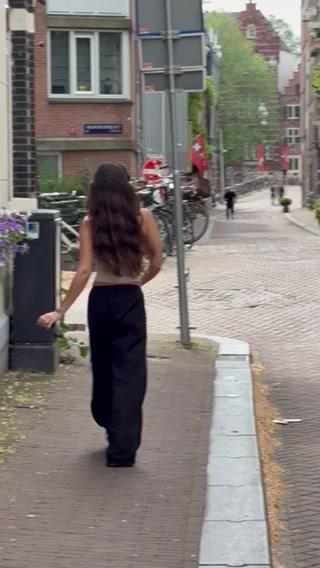 A woman walks down a cobblestone street lined with buildings and bicycles